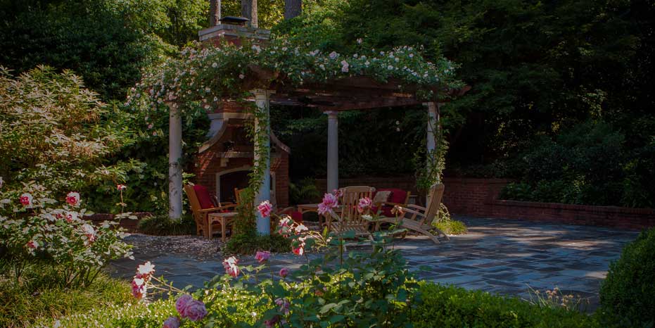 A rose pergola covers a sitting area for outdoor entertaining